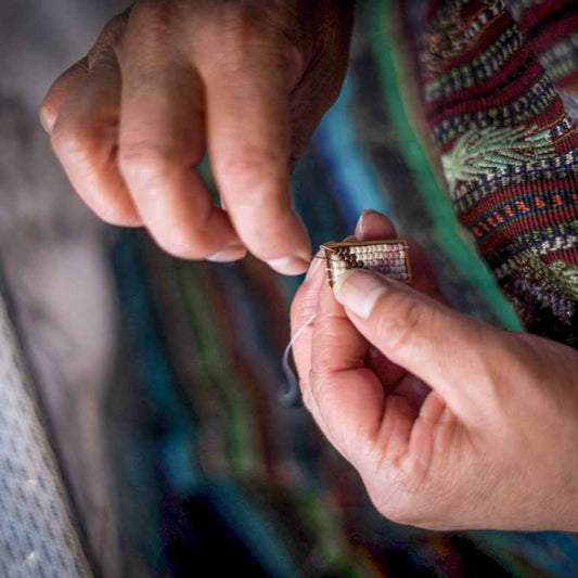 Artisan woman weaving beaded earrings.