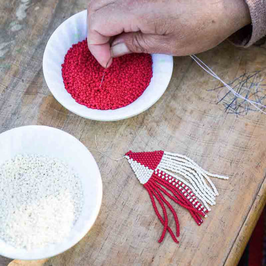 Guatemalan artisan weaving beaded earrings at a fair trade women's cooperative.