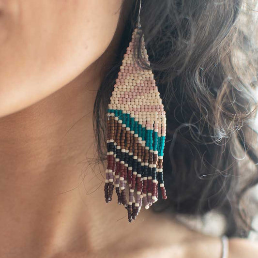 Close-up of a person wearing a beaded earring with a blurred background