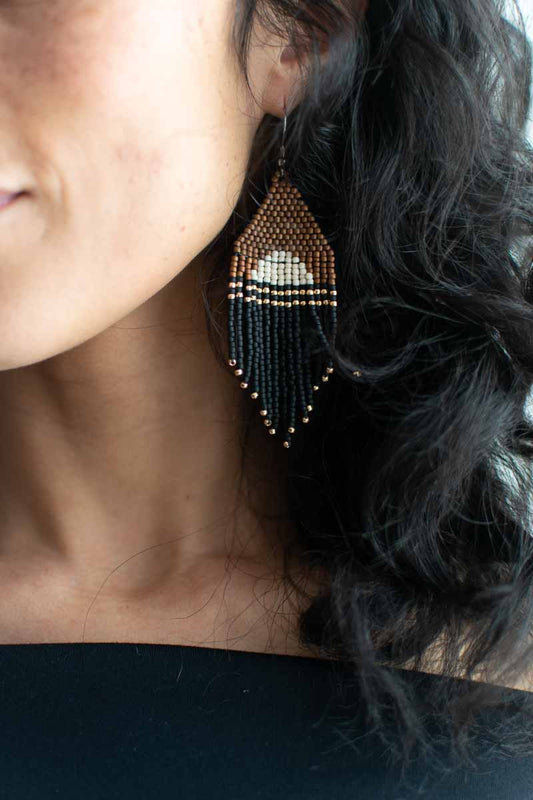 Close-up of a person wearing beaded earrings with dark hair.