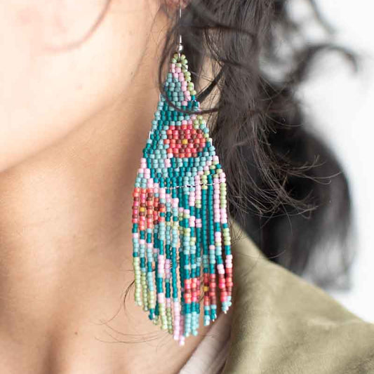 Close-up of colorful beaded earrings worn by a person with a blurred background