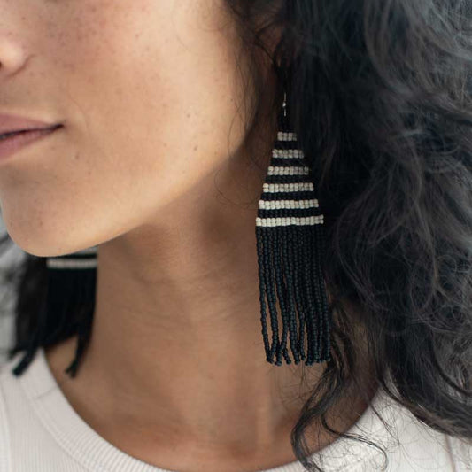 Striped beaded earrings modeled on a woman.