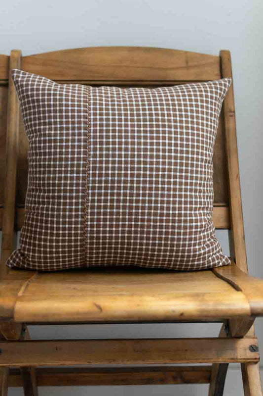 Checkered pillow on a wooden chair against a plain background