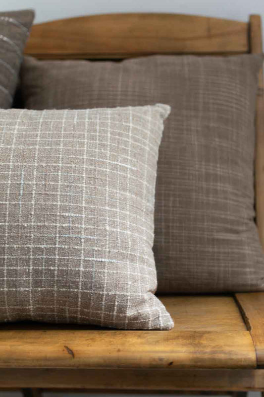 Textured pillows on a wooden bench with a neutral background