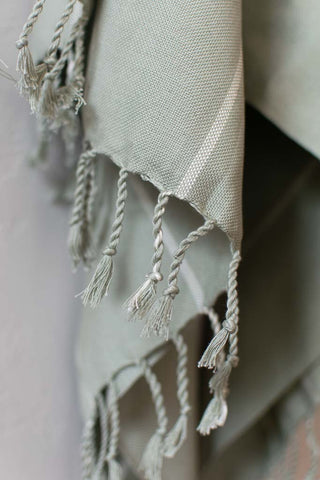 handwoven textile with fringe in sage green