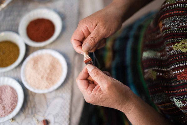 artisan weaving beaded earring in fair trade coop