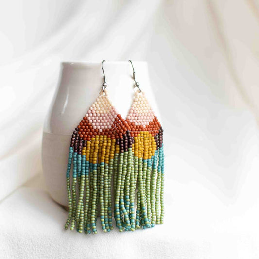 Beaded earrings that look like a sunrise with beige, pink, orange, yellow, purple, green, and turquoise blue seed beads.
