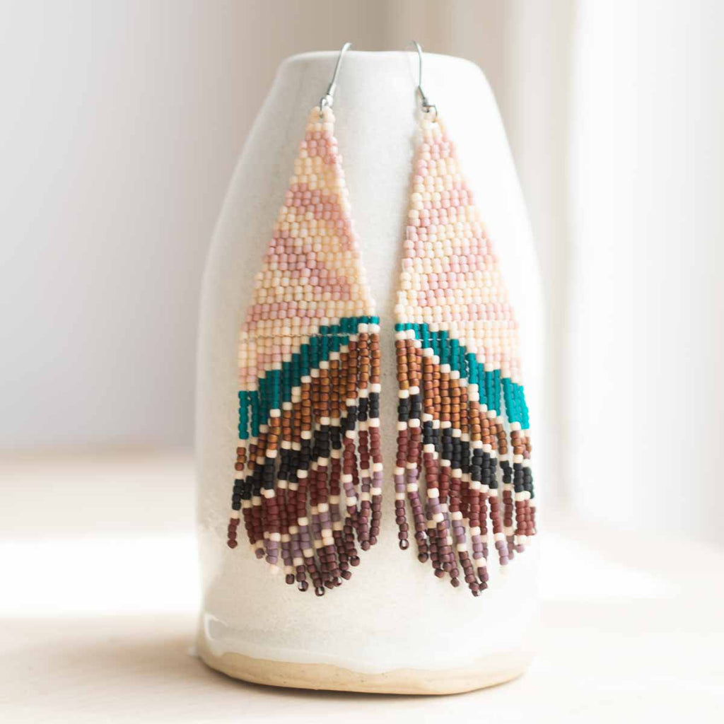 Beaded earrings on a white vase with a plain background