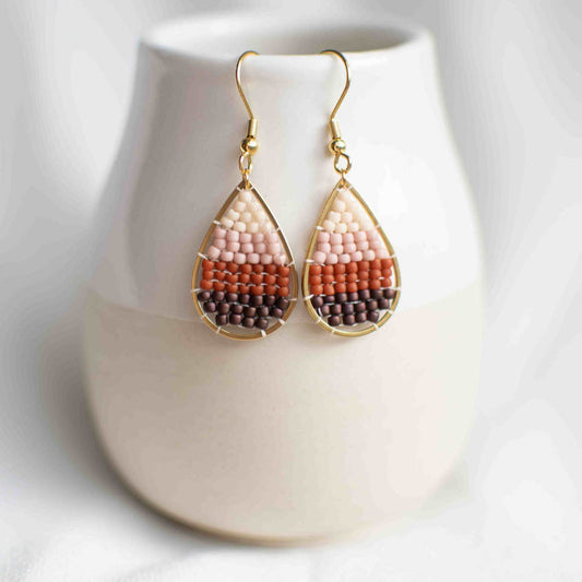 Beaded earring in pink, red, and purple inside a teardrop gold plated charm.