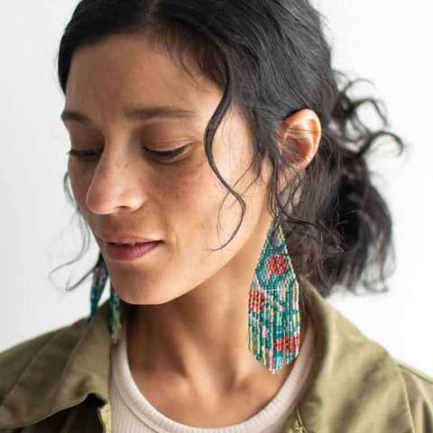 Woman wearing colorful earrings with a neutral background