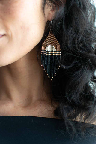 Close-up of a person wearing beaded earrings with dark hair.