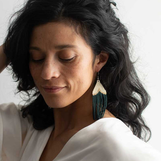 Woman wearing a white top and large beaded earrings