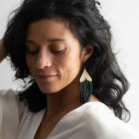 Woman wearing a white top and large beaded earrings