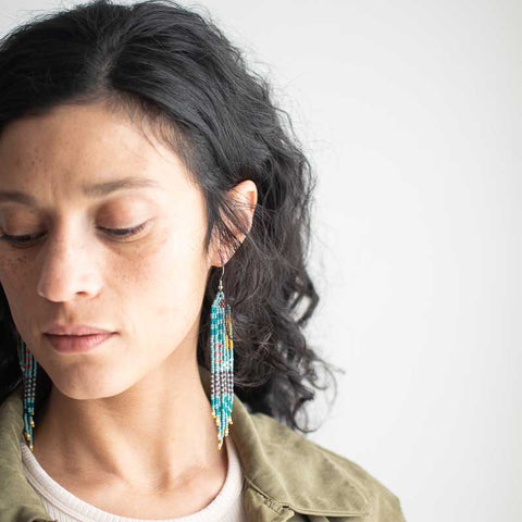 Woman wearing colorful earrings against a plain background