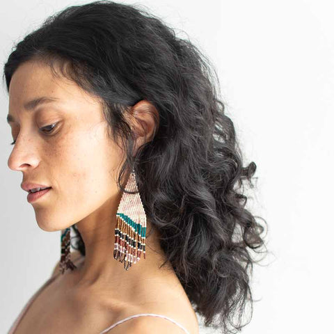Woman wearing colorful earrings with a neutral background