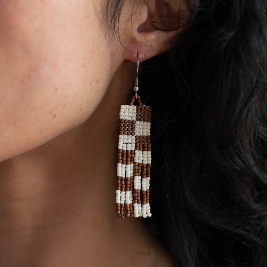 Close-up of an ear wearing a beaded earring with a dark background