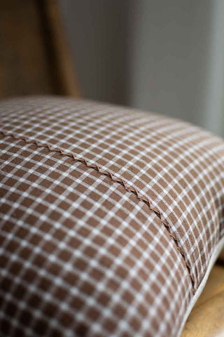 Close-up of a brown checkered fabric with visible stitching on a wooden surface.