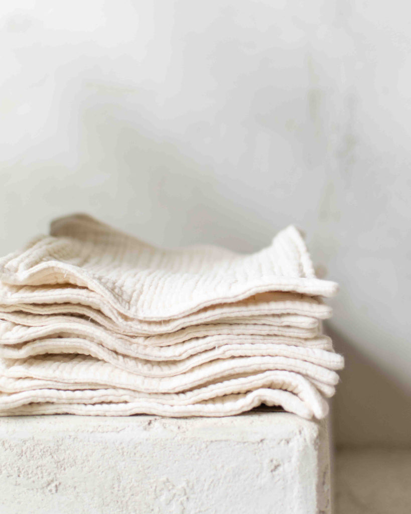 stack of organic gauze wash cloths on stucco
