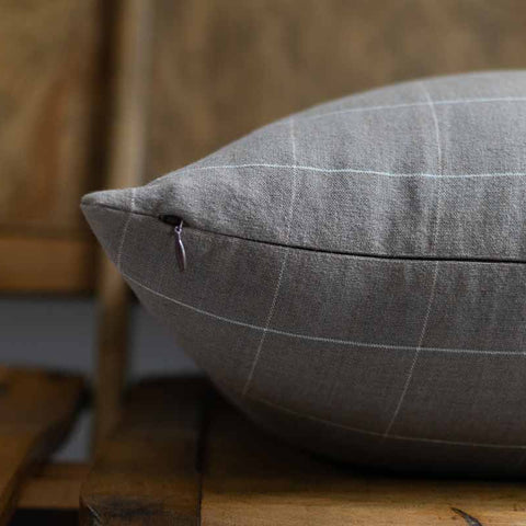 Gray checkered pillow on a wooden surface with a blurred background
