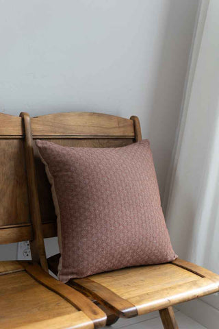 Brown cushion on a wooden chair against a white wall