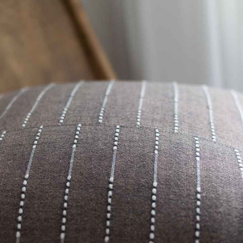 Close-up of a brown fabric with white pinstripes, possibly a chair or sofa cushion.