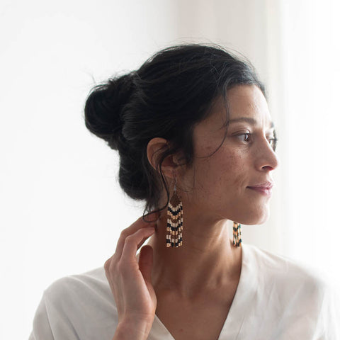Woman wearing a white blouse with a striped beaded earrings