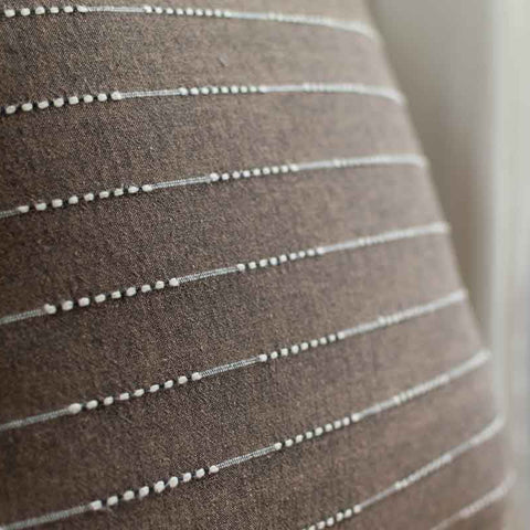 Close-up of brown fabric with white stripes on a blurred background