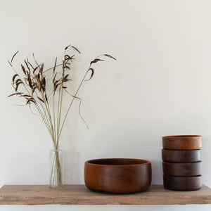 Wooden salad bowl set on shelf with vase of ocean grass