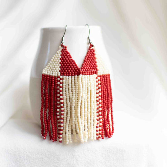 Beaded earrings in a red and off-white, high contrast pinwheel design.