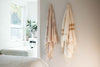 fair trade bath towels hung on hooks by bath tub
