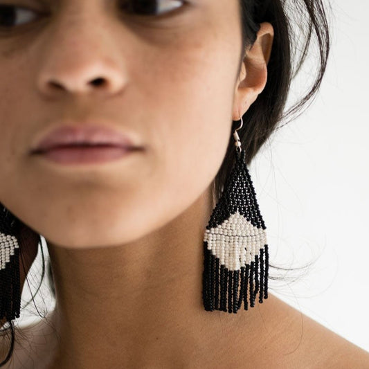 Beaded earrings in black and white modeled on a woman.