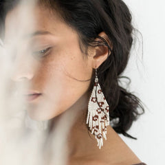 Beaded woven earrings modeled on a woman. 