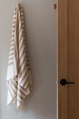 handwoven bath towel hanging on hook in minimal house