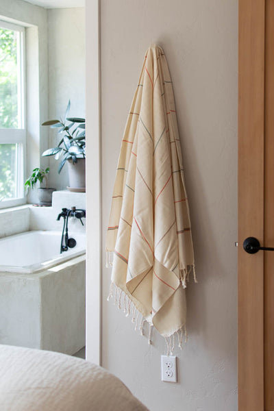 handwoven bath towel hanging on hook in minimal house