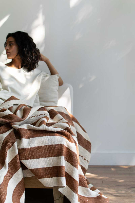 woman sitting on couch with wide striped organic blanket