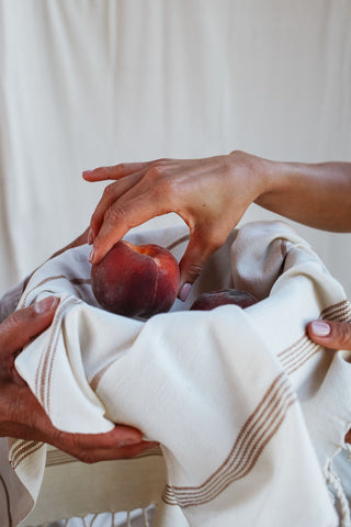 hands wrapping up peaches in a towel