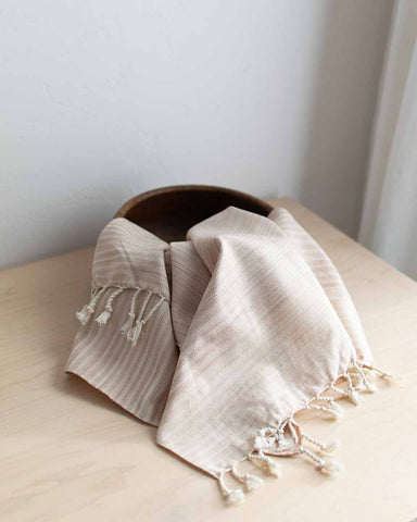 handwoven hand towel with naturally dyed coconut husks in a bowl on a table